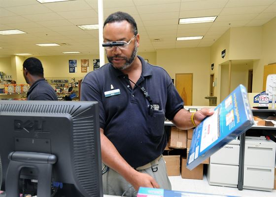 Photo of a low vision man on the job at standing at a workstation