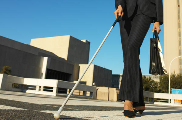 Photo of vision impaired professional walking with white cane and briefcase